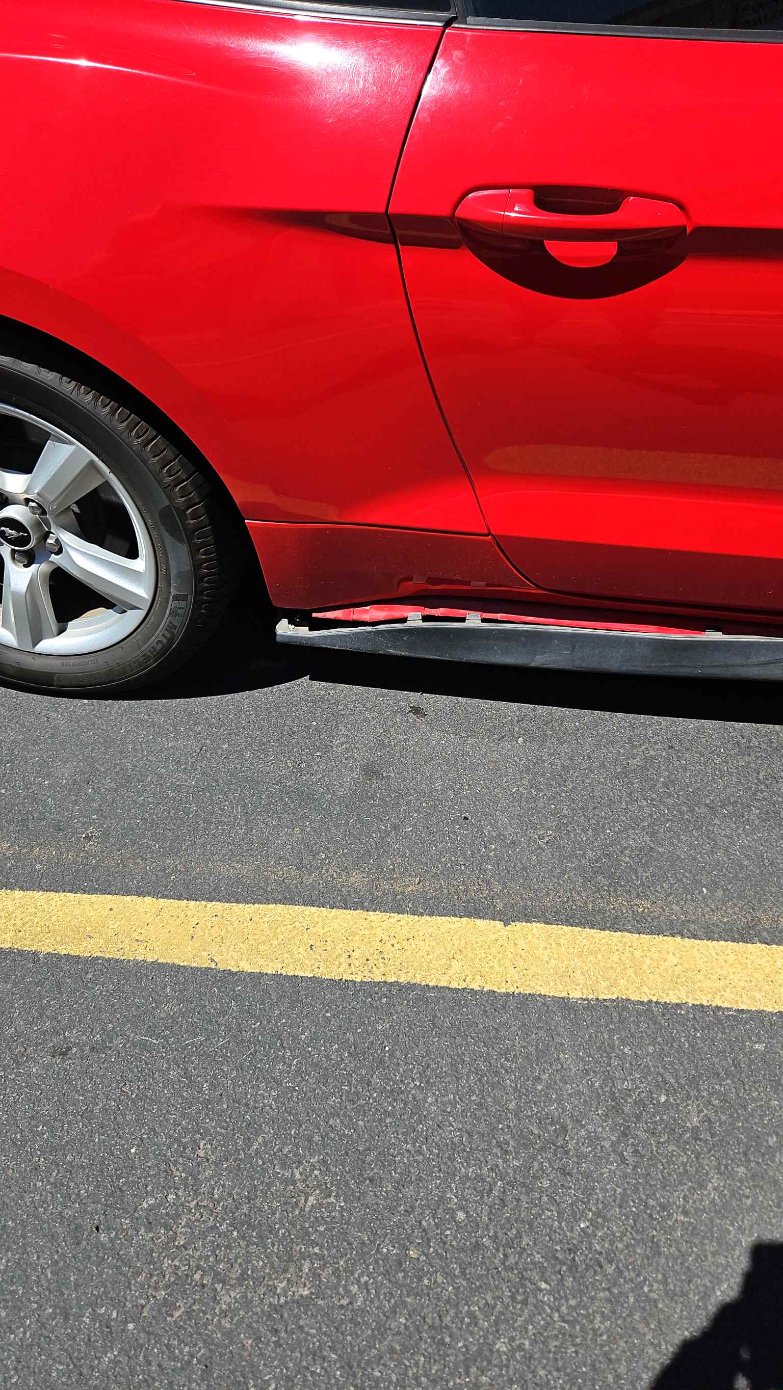 red vehicle showing damaged rocker panel and door sill before repair