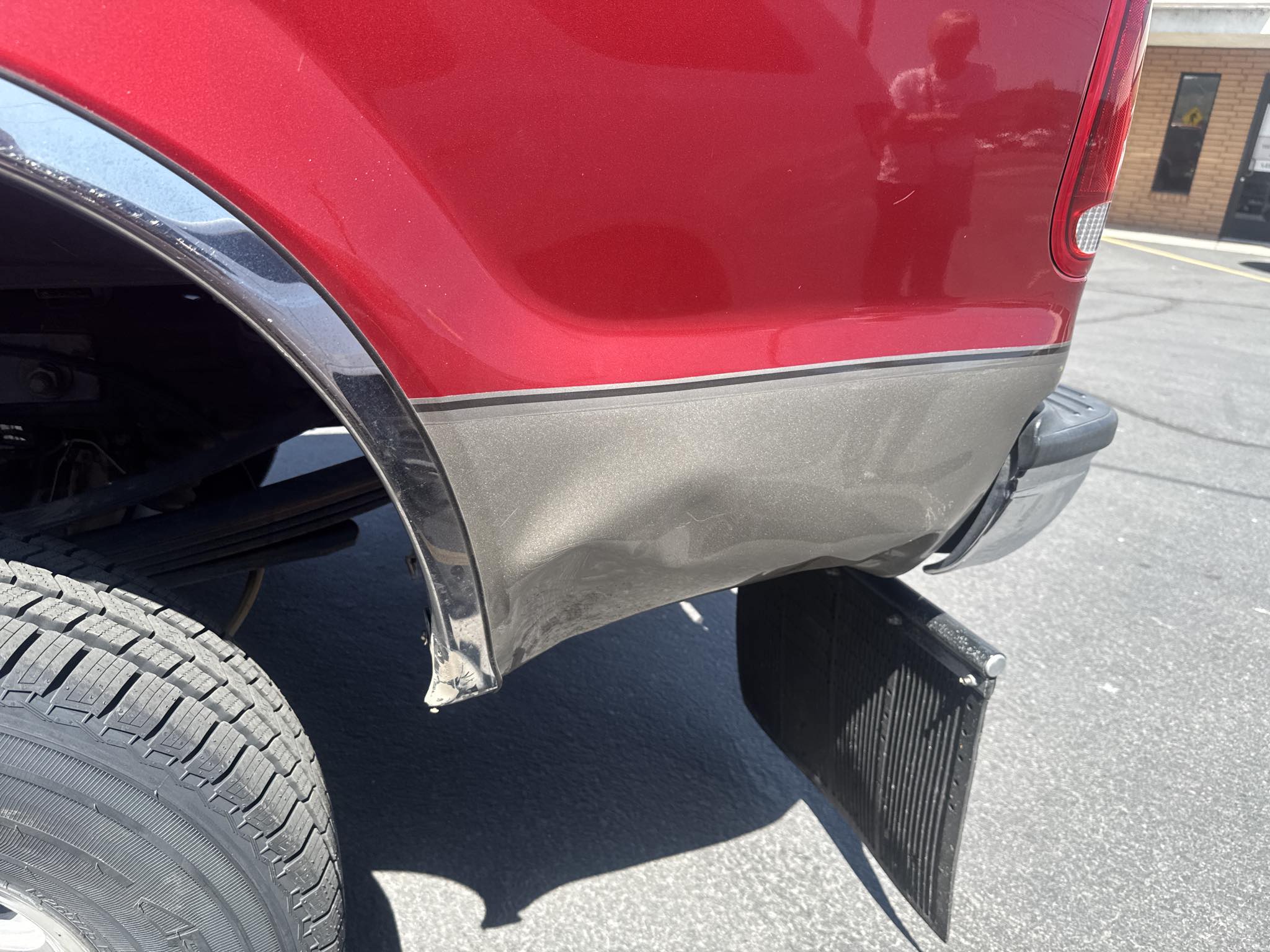 red pickup truck with damaged rear quarter panel and bumper before repair