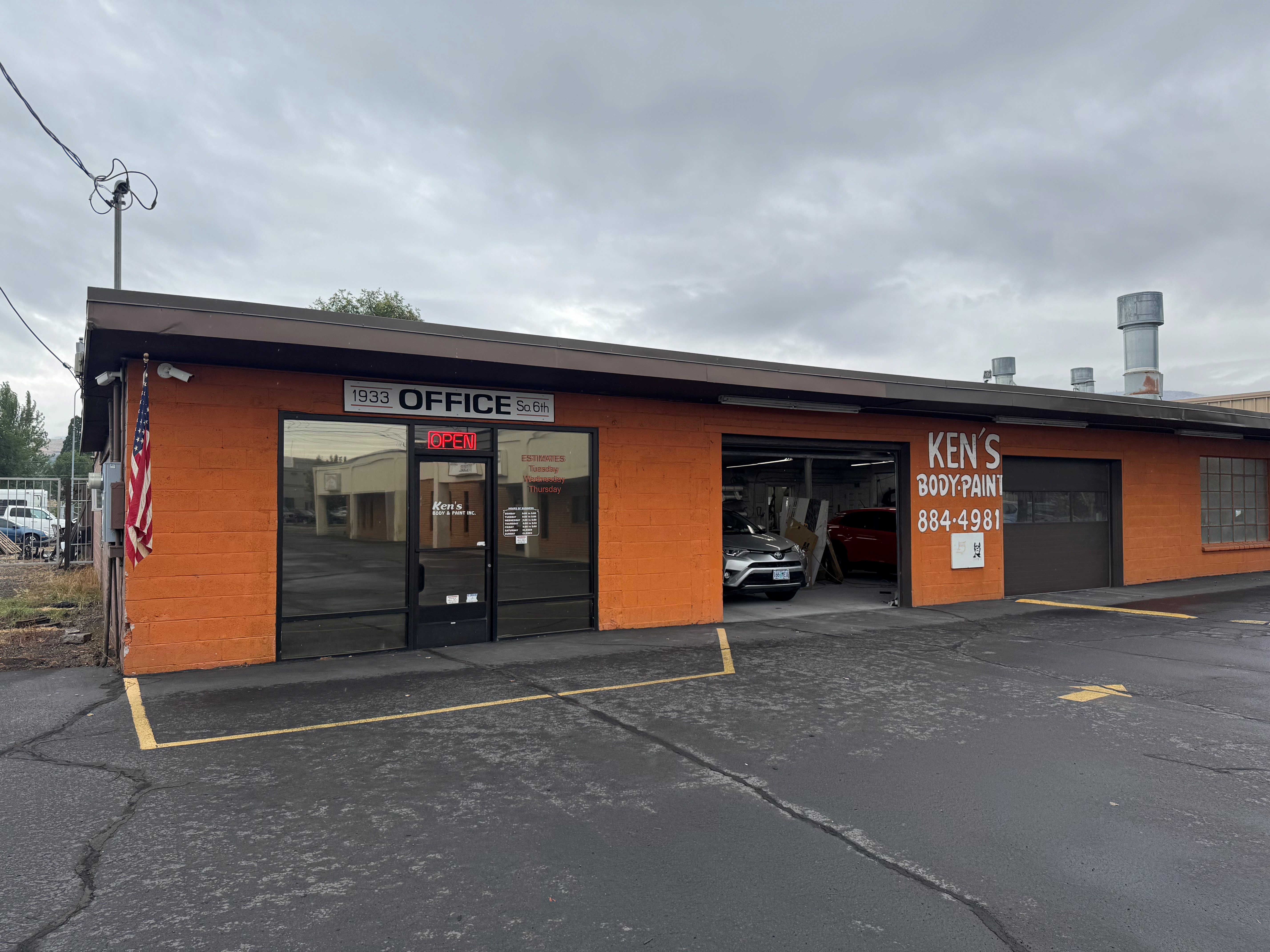 professional auto body shop exterior with team members standing proudly in front, bright lighting, modern facility